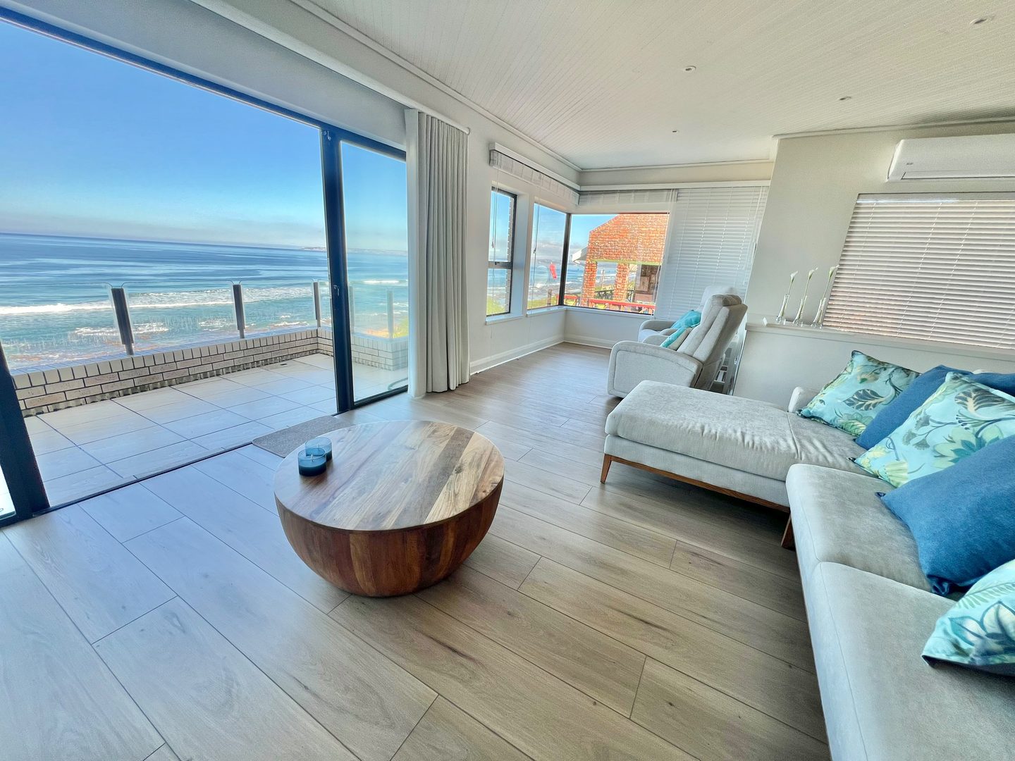 The upstairs lounge with the ocean through the glass, doors open to the balcony